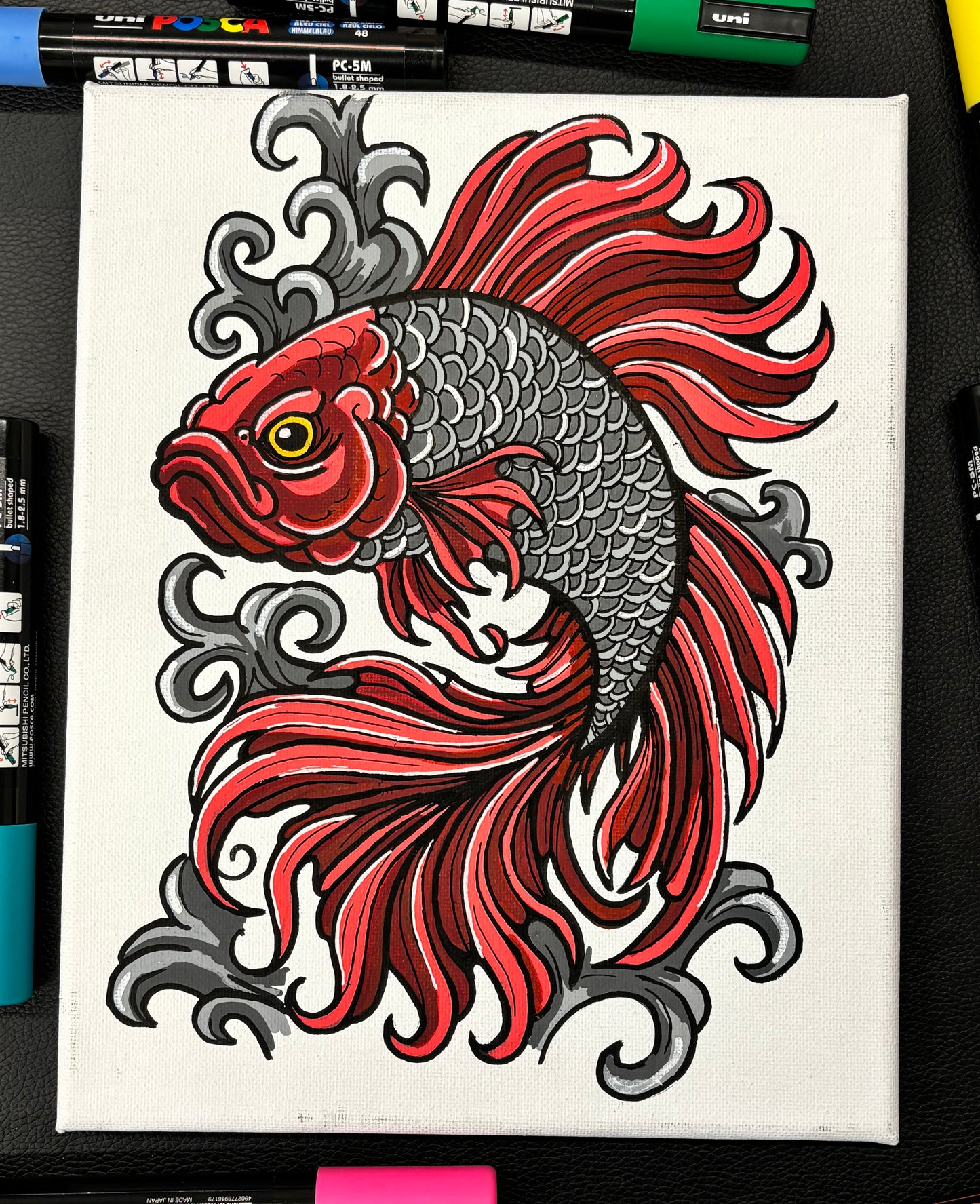 Colorful betta fish design on a white background with markers visible below.